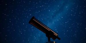 Telescope under a starry sky for astronomy enthusiasts.