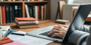 Person typing on a laptop in a cozy workspace.