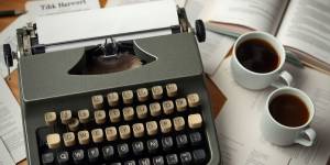 Vintage typewriter with coffee and scattered pages.